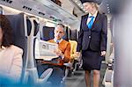 Attendant checking on businessman reading newspaper on passenger train