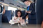 Businesswoman with smart phone using contactless payment, paying attendant on passenger train