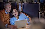 Affectionate couple watching movie on digital tablet on on passenger train at night