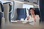 Businesswoman video chatting with headphones and smart phone on passenger train