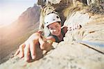 Portrait smiling, confident rock climber reaching for rock