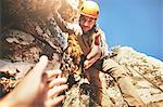 Personal perspective reaching for hand of rock climber