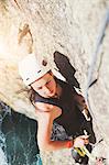 Determined, focused female rock climber scaling rock
