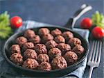 Homemade roasted beef meatballs in cast-iron skillet on dark blue background. Copy space for text. Shallow DOF