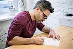 Young Designer Drawing the Sketch Using Pencil on the Wooden Table in the Bright Studio