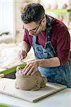 Ceramist Dressed in an Apron Sculpting Statue from Raw Clay in the Bright Ceramic Workshop.