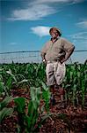 Black farmer stands smiling in a crop field with irrigation systems in the background