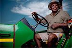 Black farmer sitting on a tractor smiling