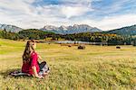 Woman sitting and staring at Gerold lake and Karwendel Alps, Krun, Upper Bavaria, Bavaria, Germany, Europe