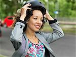 Mid adult woman putting on bicycle safety helmet