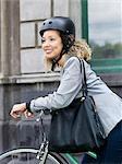 Mid adult woman sitting on bicycle, wearing safety helmet