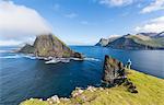 Man looks towards the sea stacks of Drangarnir and Tindholmur islet, Vagar Island, Faroe Islands, Denmark, Europe