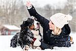 Woman hugging her dog in the snow on winter day