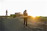 Young female runner running down rural road at sunset, Las Palmas, Canary Islands, Spain