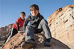 Portrait of boys sitting on rock looking at camera, sticking out tongue, Lone Pine, California, USA