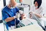 Dentist and dental nurse carrying out procedure on male patient