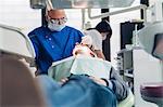 Dentist carrying out dental procedure on male patient