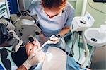 Dentist and dental nurse carrying out dental procedure on female patient