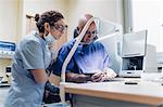 Dentist polishing denture in laboratory, female dentist watching process