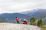 Boy helping hiker father over rock in mountain landscape, Jotunheimen National Park, Lom, Oppland, Norway