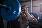 Man exercising in gym, using barbell, front squat position