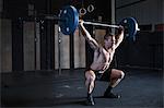 Man exercising in gym, using barbell, front squat position