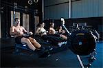 Group of people exercising in gymnasium, using rowing machines