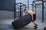 Man exercising in gymnasium, lifting tire