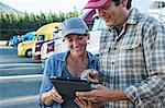 Caucasian woman and man truck driving team working on their driving log in a truck stop parking lot.