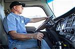 Caucasian man truck driver in the cab of his commercial truck.