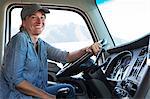 Caucasian woman truck driver in the cab of her commercial truck at a truck stop