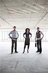 Mixed race team of business people in their new large empty raw office space.