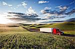 Commercial truck driving through farmlands in eastern Washington, USA at sunset.