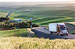 Commercial truck driving though wheat fields of eastern Washington, USA at sunset.