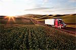 Peterbilt Class8 commercial truck driving through farmlands in eastern Washington, USA at sunset.