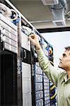 Male computer technician working on servers in a computer server farm.