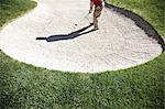 Senior golfer playing out of a bunker on the golf course.