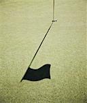 Shadow of a golf flag on the green of a golf course.