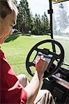 Senior golfer recording his score on a score card in a golf cart.