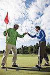 A senior couple doing a fist bump after making putt on a green.