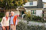 Hispanic senior couple in front of their remodelled older style home.