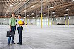 Black woman and Asian woman standing inside of a brand new empty warehouse.