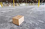 Single cardboard box in the middle of a new empty warehouse space.