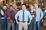 Mixed race team of workers and management people in a large sheet metal factory