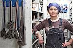 Black woman factory worker wearing coveralls in a large sheet metal factory.