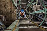 Factory worker climbing up a ladder in a sheet metal factory.