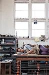 Black woman factory worker taking a nap on top of a work station in a woodworking factory.