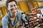 View of a smiling black woman factory worker at her work station in a woodworking factory.