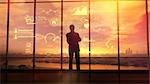 Silhouette of a man in a huge office in front of large windows viewing corporate infographics.