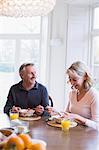 Smiling mature couple eating breakfast at dining table